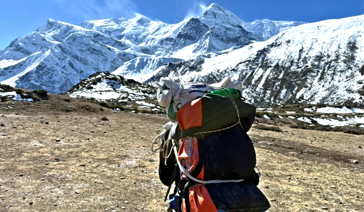 A porter carrying a duffel bag and hiking in annapurna circuit trail