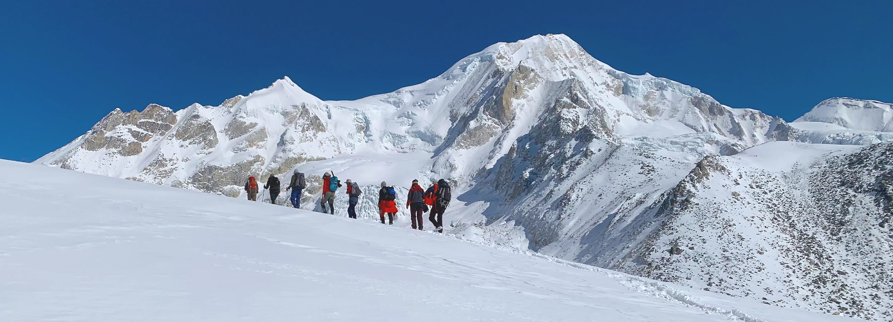 Manaslu region trekking trail with trekkers hiking up and himalayan panorama