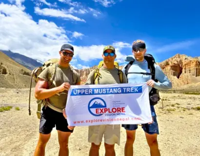 Upper Mustang Trek group with Explore Vision Nepal banner surrounded by Himalayan landscapes