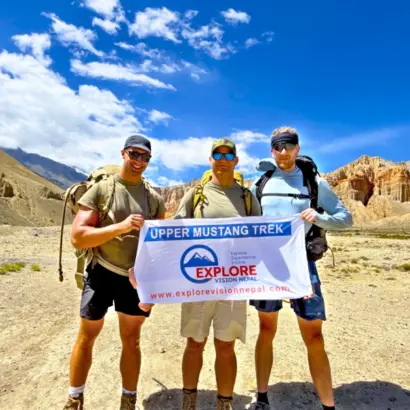 Upper Mustang Trek group with Explore Vision Nepal banner surrounded by Himalayan landscapes