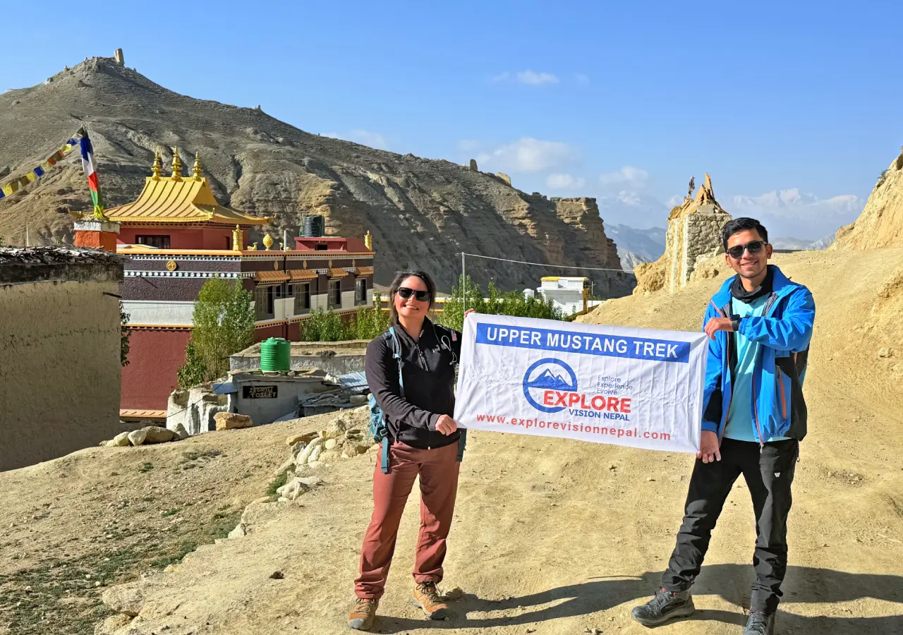 Trekkers with Explore Vision Nepal banner at a monastery during the Upper Mustang Trek in Mustang Nepal