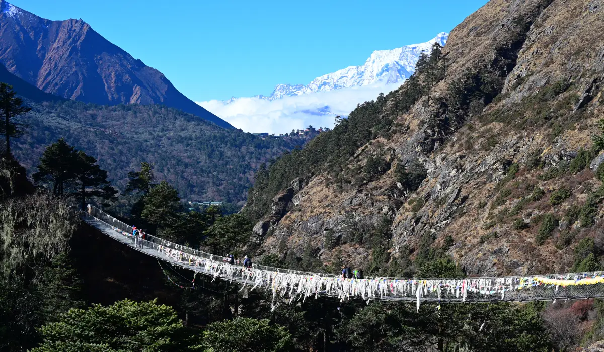 Trekkers crossing a suspension bridge on the Everest Base Camp Trek, crossing suspension bridges is one of the Everest Base Camp trek difficulty for some trekkers