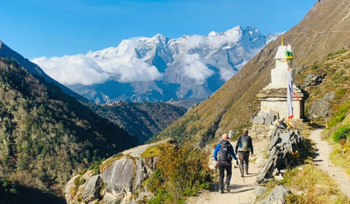 Trekkers walking through the Everest Base Camp trail with mountains and Buddhist stupa and enjoying the spectacular mountain view