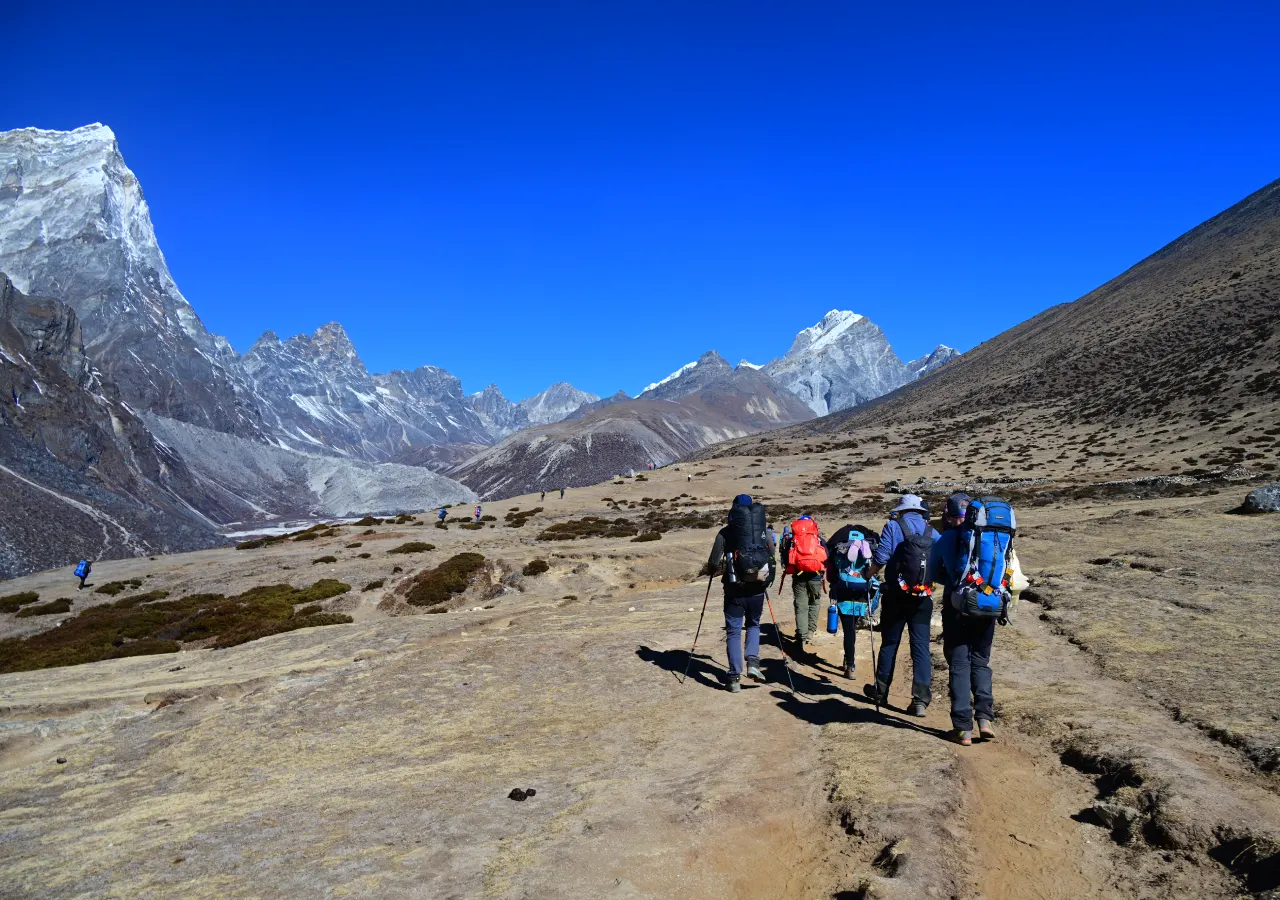 Trekkers walking through a Himalayan valley on the Everest Base Camp Heli Trek with Himalayan mountains view around the trail